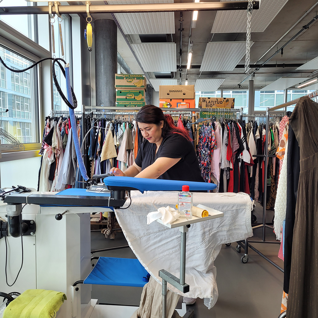 Femme repassant des vêtements pour la boutique vêtementssecondemainGenève donnervêtementsGenève collectevêtementsGenève achatsolidaireGenève économiecirculaireGenève secondevievêtementsGenève boutiquesecondemainGenève friperieGenève donsolidaireGenève RenfileGenève
