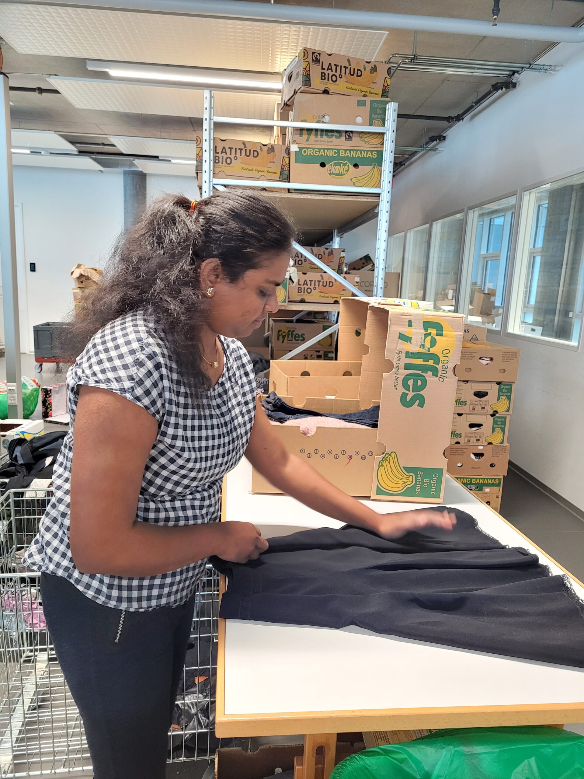 Femme pliant un vêtement pour la boutique vêtementssecondemainGenève donnervêtementsGenève collectevêtementsGenève achatsolidaireGenève économiecirculaireGenève secondevievêtementsGenève boutiquesecondemainGenève friperieGenève donsolidaireGenève RenfileGenève