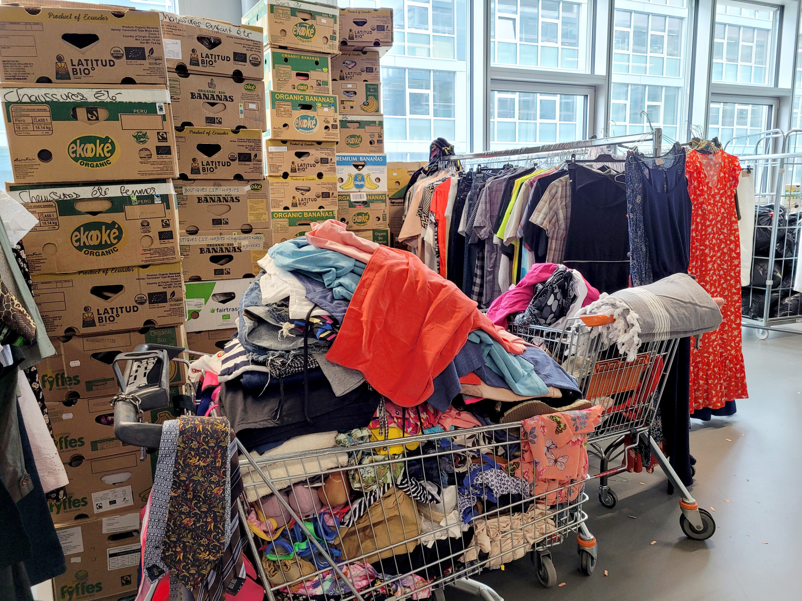 Grand tas de vêtements et boîtes en carton en attente de sélection vêtementssecondemainGenève collectevêtementsGenève donnervêtementsGenève achatsolidaireGenève économiecirculaireGenève secondevievêtementsGenève boutiquesecondemainGenève friperieGenève donsolidaireGenève RenfileGenève